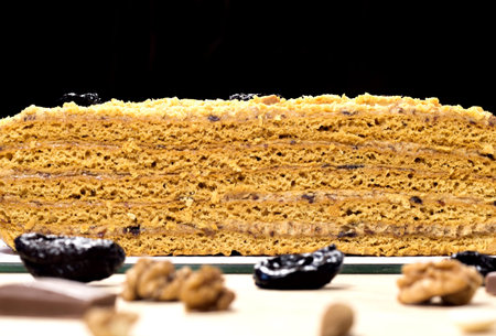 Delicious honey cake divided with prune and nuts on black backgroundの写真素材