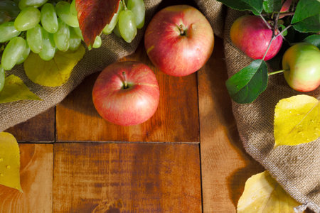 Fresh harvest of apples. Nature theme with green grapes and apple on wooden background. Nature fruit...
