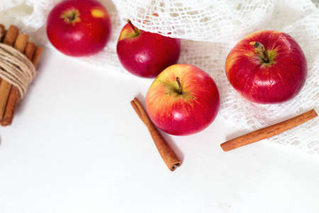 Fresh ripe red apples and cinnamon sticks on white wooden background.の写真素材