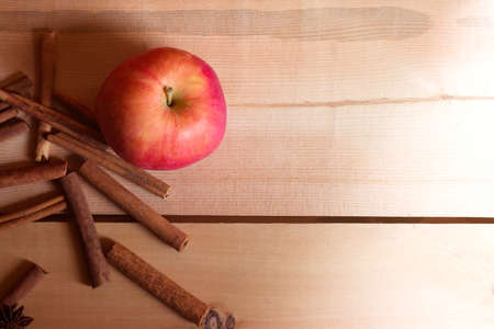 Fresh ripe red apples and cinnamon sticks on wooden backgroundの写真素材