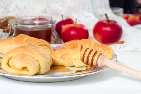 Freshly baked homemade sweet buns with apple seeds and honey on white table in saucerの写真素材