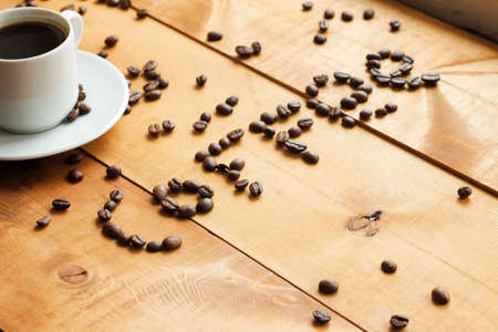 Coffee cup and coffee beans on wooden tableの写真素材