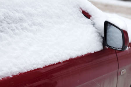 Frozen car covered snow in winter day, view front window windshield and hood on snowy backgroundの写真素材