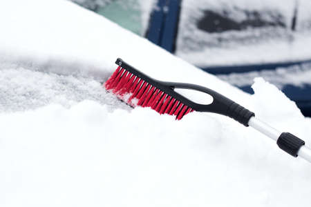 Closeup photo of black brush lying on car covered in snowの写真素材