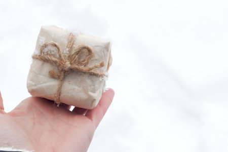 top view hand woman holding brown gift box for new year on snow background with space.
