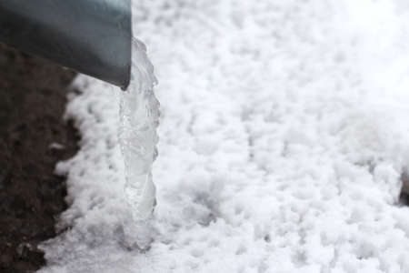 frozen water in a drainpipe, with hanging iciclesの写真素材