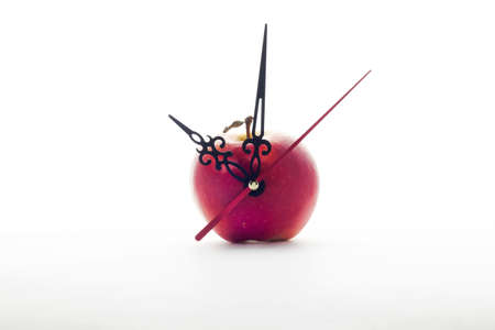 red ripe apple and clock hands on white background . Time concept or healthy food or detox conceptsの写真素材