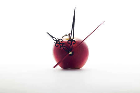 red ripe apple and clock hands on white background . Time concept or healthy food or detox conceptsの写真素材