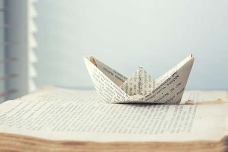 a paper ship is sent to the path of knowledge and words on sea book background conceptの写真素材