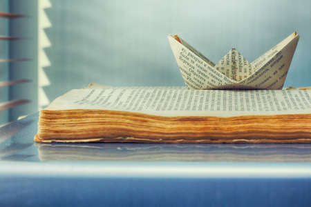 The old book and the paper ship of words go on a journey of thoughtsの写真素材