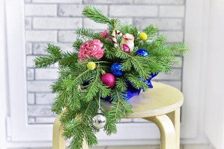 Bouquet of Christmas tree with Christmas decorations and live carnations and roses. On light background. The concept of gift and celebration.の写真素材