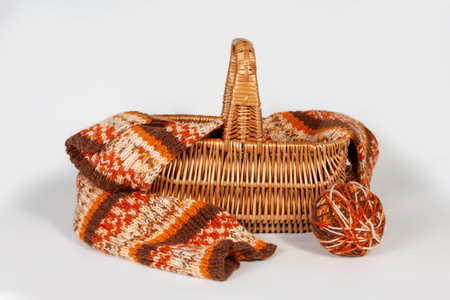 Knitting balls of yarn, brown knitted scarf in a basket on a gray background. Knitted and winter...