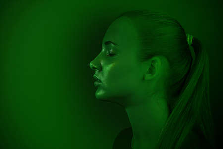 Young beautiful girl posing in a Studio with creative lighting. Artistic design, fashionable green tintingの写真素材