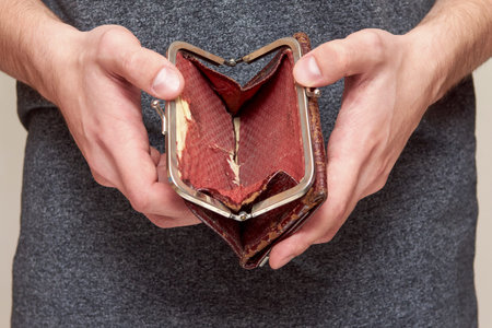 An old shabby brown purse in the hands of a man, the Concept of crisis, unemployment, lack of...
