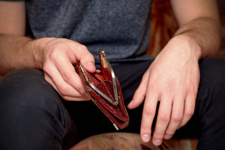 An old shabby brown purse in the hands of a man, the Concept of crisis, unemployment, lack of...