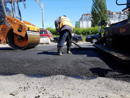Chelyabinsk, Russia, June 06, 2020. Road repairs as part of the urban development repair program. Cars are laying new asphalt on the road.のeditorial素材