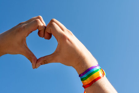 Gay pride concept. Hand making a heart sign with gay pride LGBT rainbow flag wristband