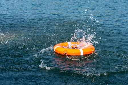 Orange lifebuoy in the sea on the water. The lifebuoy fell with a splash to the surface of the...