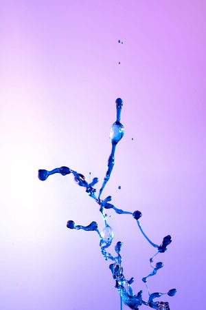 abstract purple background of blue water splash, collision of colored drops. Close up.
