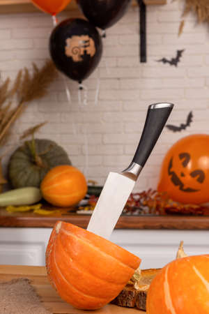 On a table decorated for Halloween, there is a pumpkin with a knife stuck in it. Im making Jacks Lantern.の写真素材