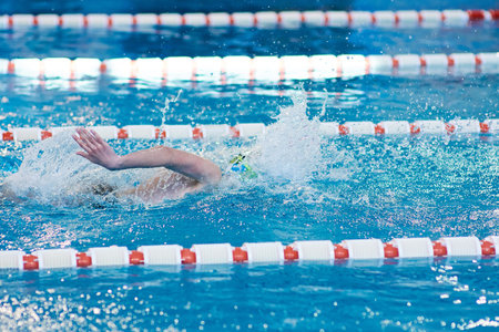 a beanie swimmer stretches his arms in the water during a breaststroke workout in the pool, blurred...