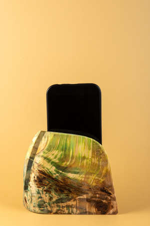 Smartphone in a stand made of stabilized maple wood on a yellow background.の写真素材