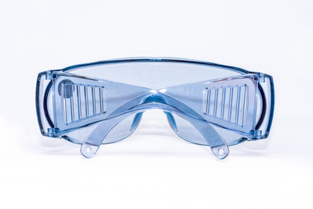 Blue plastic safety glasses on a white background isolated, close -up. Concept of occupational...