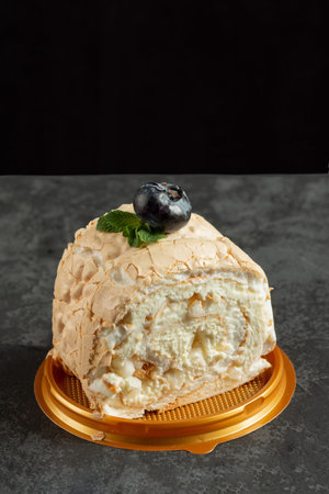 Meringue roll cake with cream on dark background. delicious dessert on the pastry shop menu. close...