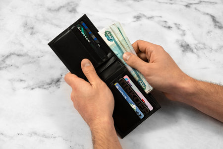 banknote money rubles and bank cards in a wallet on a light background, the concept of saving money and business growth, the concept of finance and investment. Chelyabinsk, Russia 06.01.2023のeditorial素材