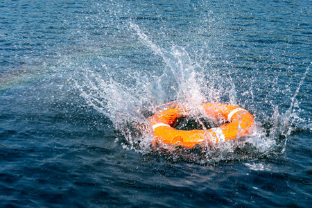 Orange lifebuoy in the sea. The rescue ring fell with a splash on the surface of the water, motion blur .の写真素材