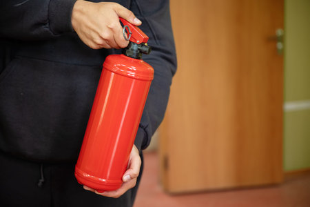 A fire extinguisher being held in an office setting, demonstrating fire safety concepts
