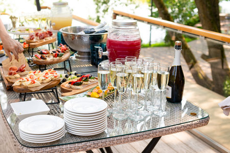 Outdoor catering table set with champagne, fruit punch, and appetizersの写真素材