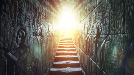 Egypt Edfu temple, Aswan. Passage flanked by two glowing walls full of Egyptian hieroglyphs, illuminated by a warm orange backlight from a doorの写真素材