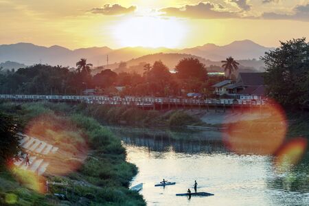 Thailand, the vicinity of Nan. Young people are kayaking on the river during sunset, against the backdrop of beautiful mountains.の写真素材