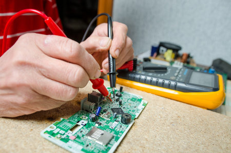 man hands closeup repair electronic device using Multimetr