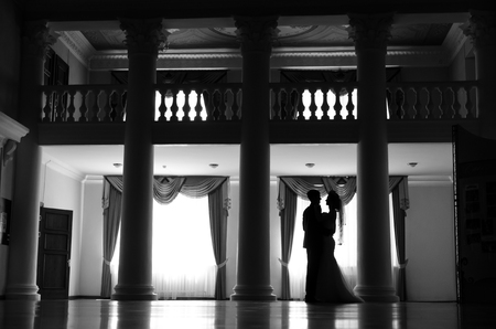silhouette of dancing couple at a window. couple hugging in a beautiful room with large skylights. wedding dayの写真素材