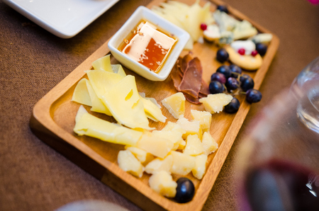 Cheese plates served with grapes, jam and nuts on a wooden background, Top viewの写真素材