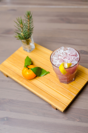 Traditional Christmas pink cocktail punch in glasses, decorated with fir tree and orange on the wooden table. the Christmas tree branches and decorationsの写真素材
