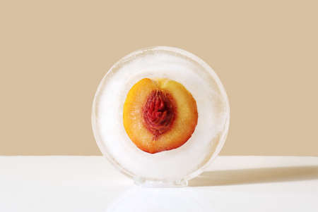 Peach with seed in round ice. Concept of shock freezing of fruits and frozen food.の写真素材