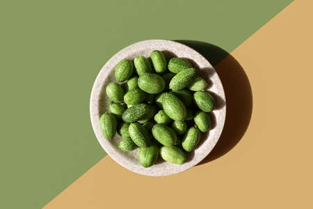 Alkaline diet, nature balance concept. Cucamelon in granite plate on double diagonal background. Organic design, green yellow colors. Eco tableware, plant. Hard light, dark shadow, flat lay posterの写真素材