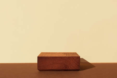 Horizontal template for mockup, banner. Wooden pedestal on brown beige background. Flat square stand or podium for natural design concept. Center composition, hard light, front viewの写真素材