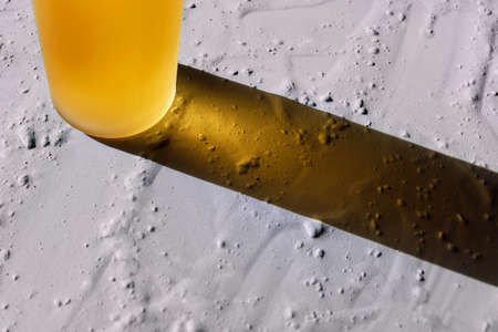 Aroma oil bottle on dried gray cosmetic clay for eco products, spa theme. Horizontal banner, poster, copy space. Texture background, orange vial of serum, lotion, essence. Long shadow, hard lightの写真素材