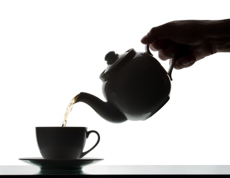 Teapot pouring tea into a cup. Silhouetteの写真素材