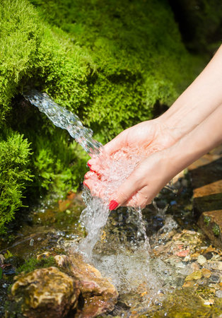 Spring water flows in female hands