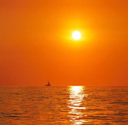 Sunset or sunrise over the sea. On the horizon a yacht.の写真素材