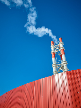 Industrial pipes and smoke on blue sky backgroundの写真素材