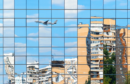 Residential buildings and plane are reflected in the mirror windowsの写真素材