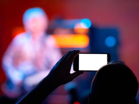 Human taking photos and videos at concertの写真素材