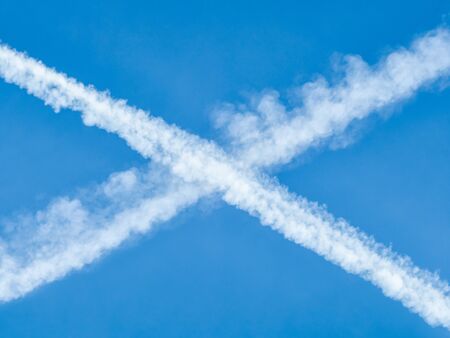 Traces of planes intersect in the blue sky の写真素材