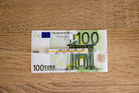 Euro currency threatened by economic crisis. Thermometer lies on 100 euro currency. EU money under...